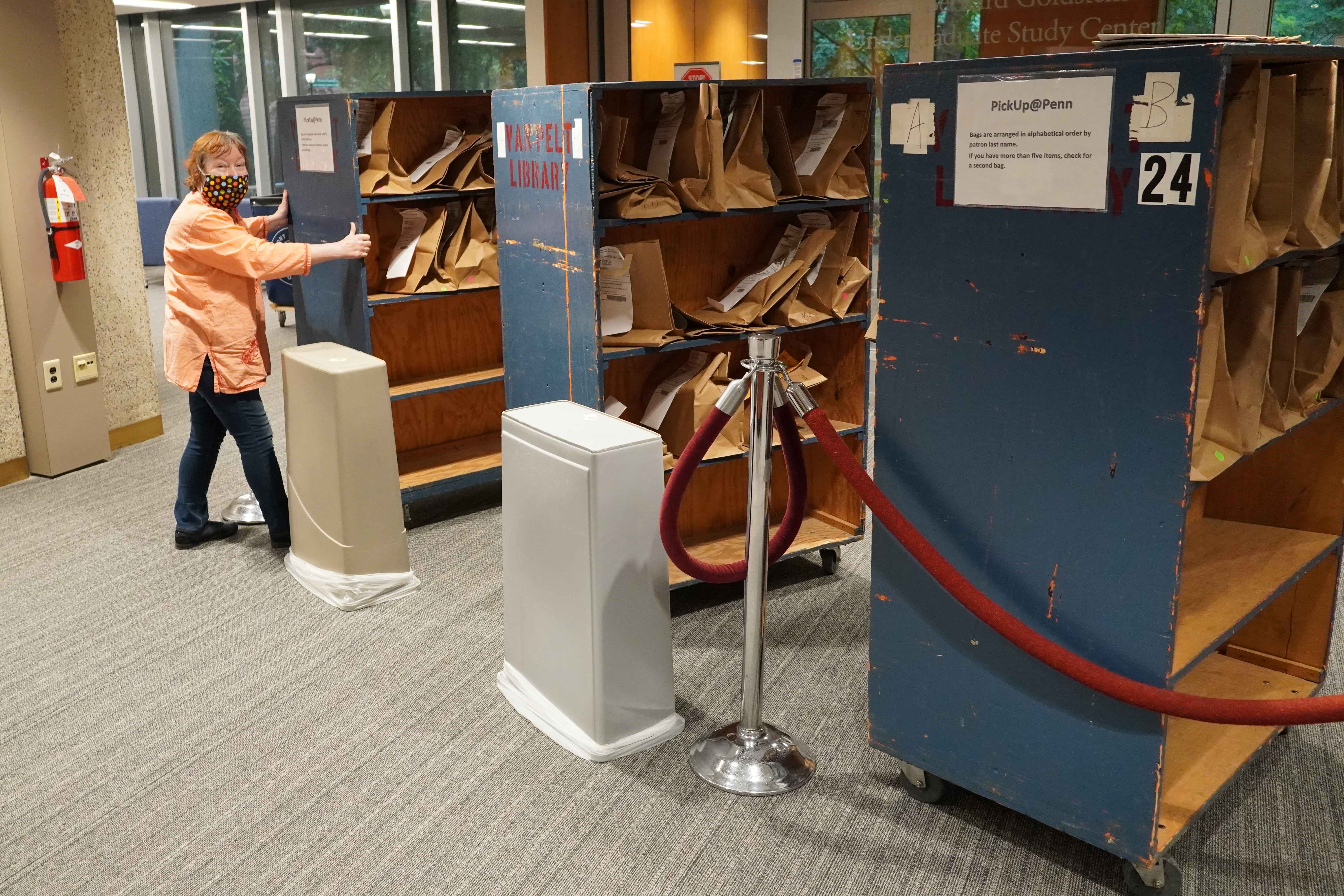 A librarian is adjusting a bookshelf to the correct position.