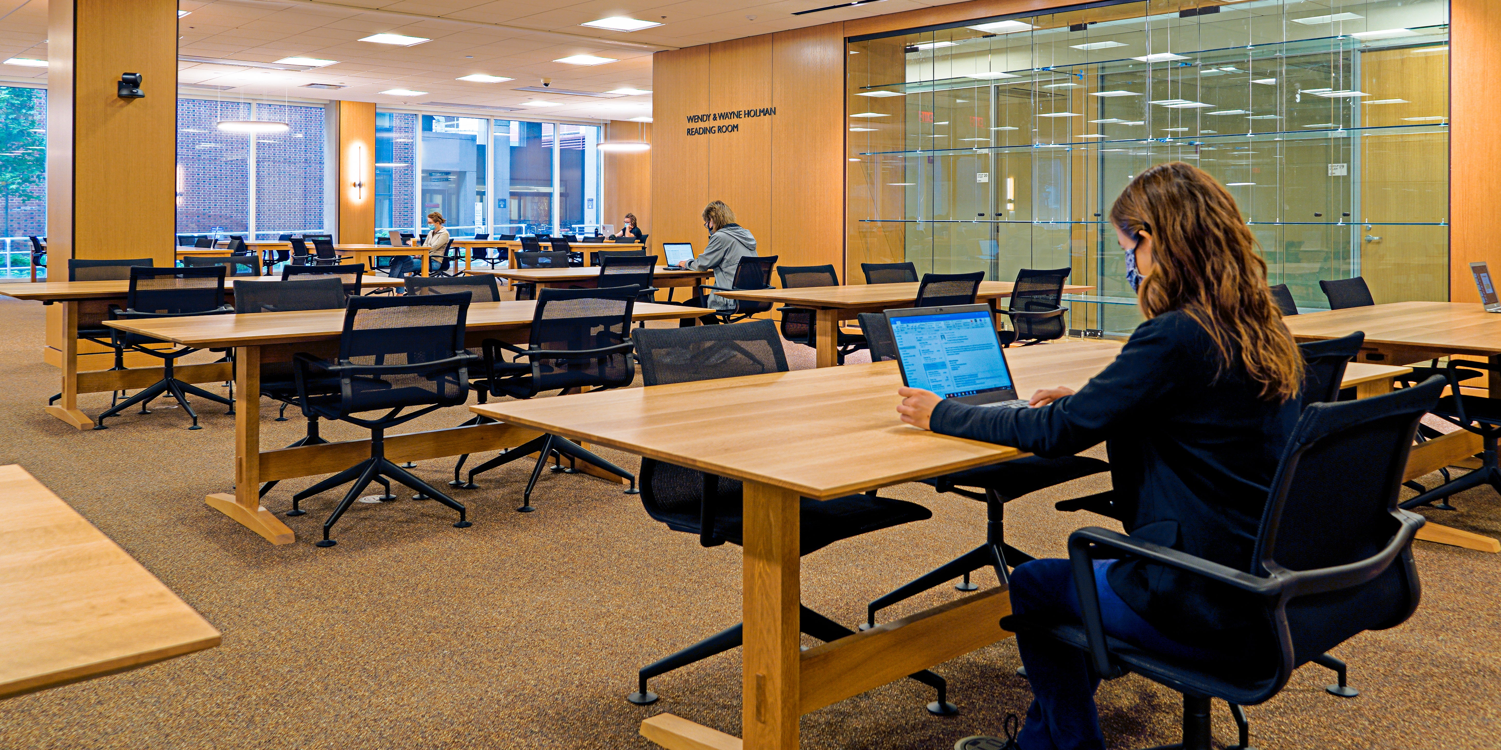 Person sitting at table with laptop in room of tables and chairs