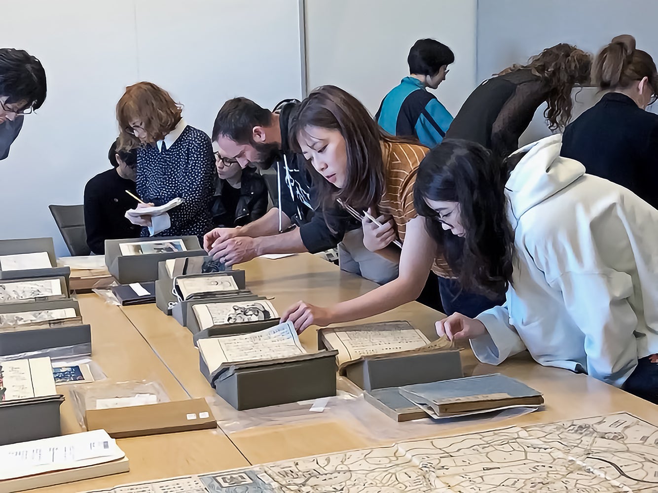 Students around tables each looking at a book on a stand