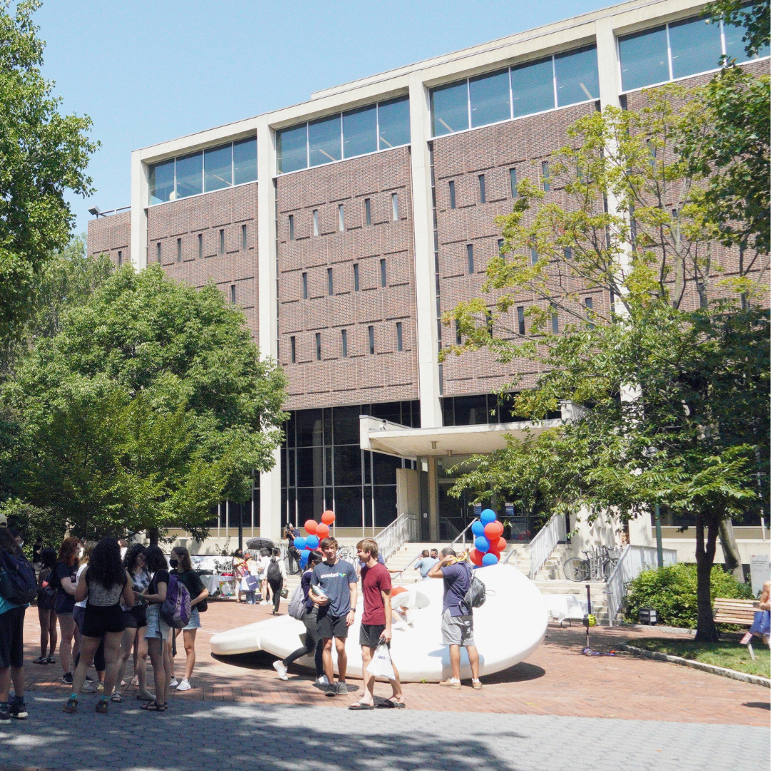 A sunny day outside Van Pelt Library. A group of people are gathered around "the Button."