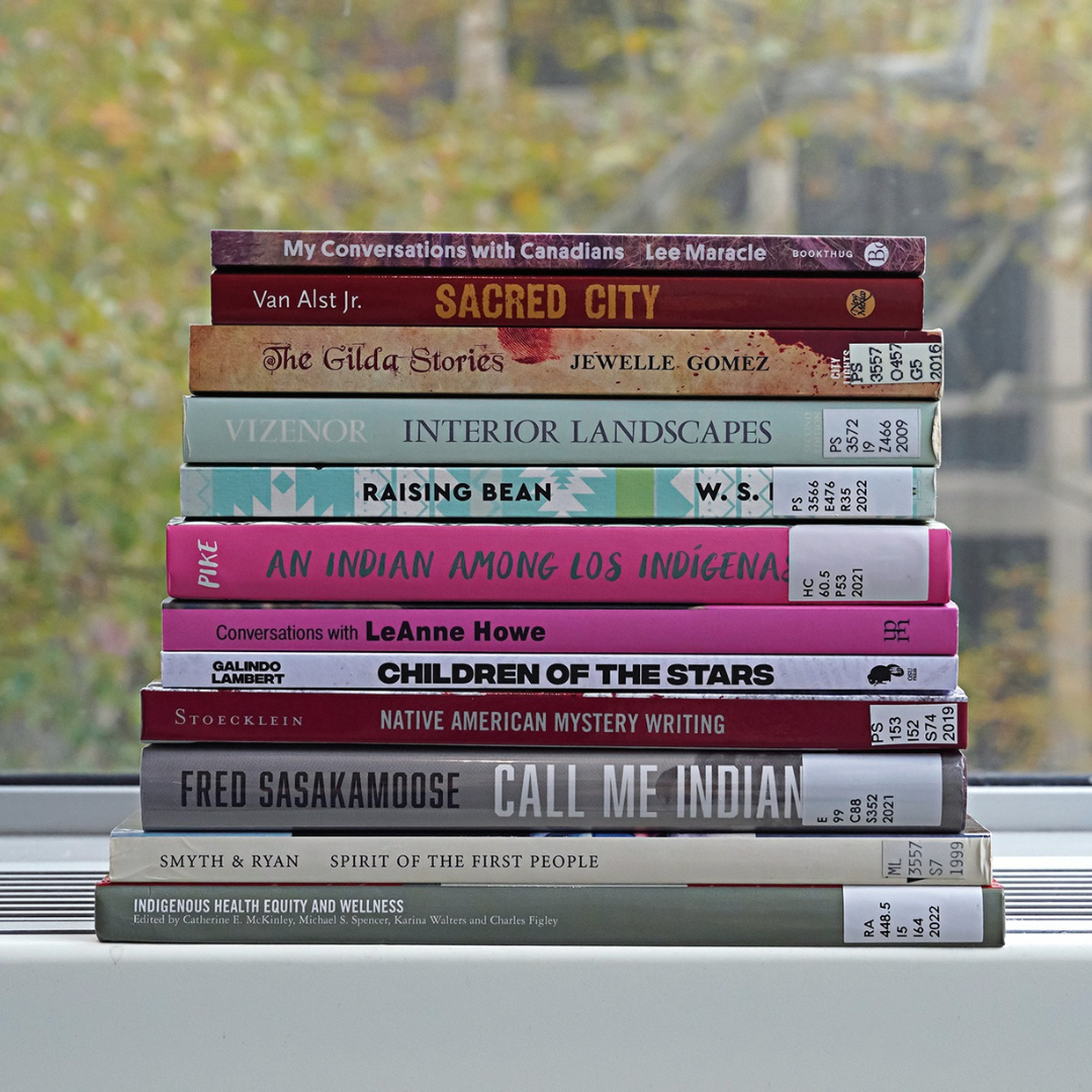 A stack of 12 books on a windowsill. 
