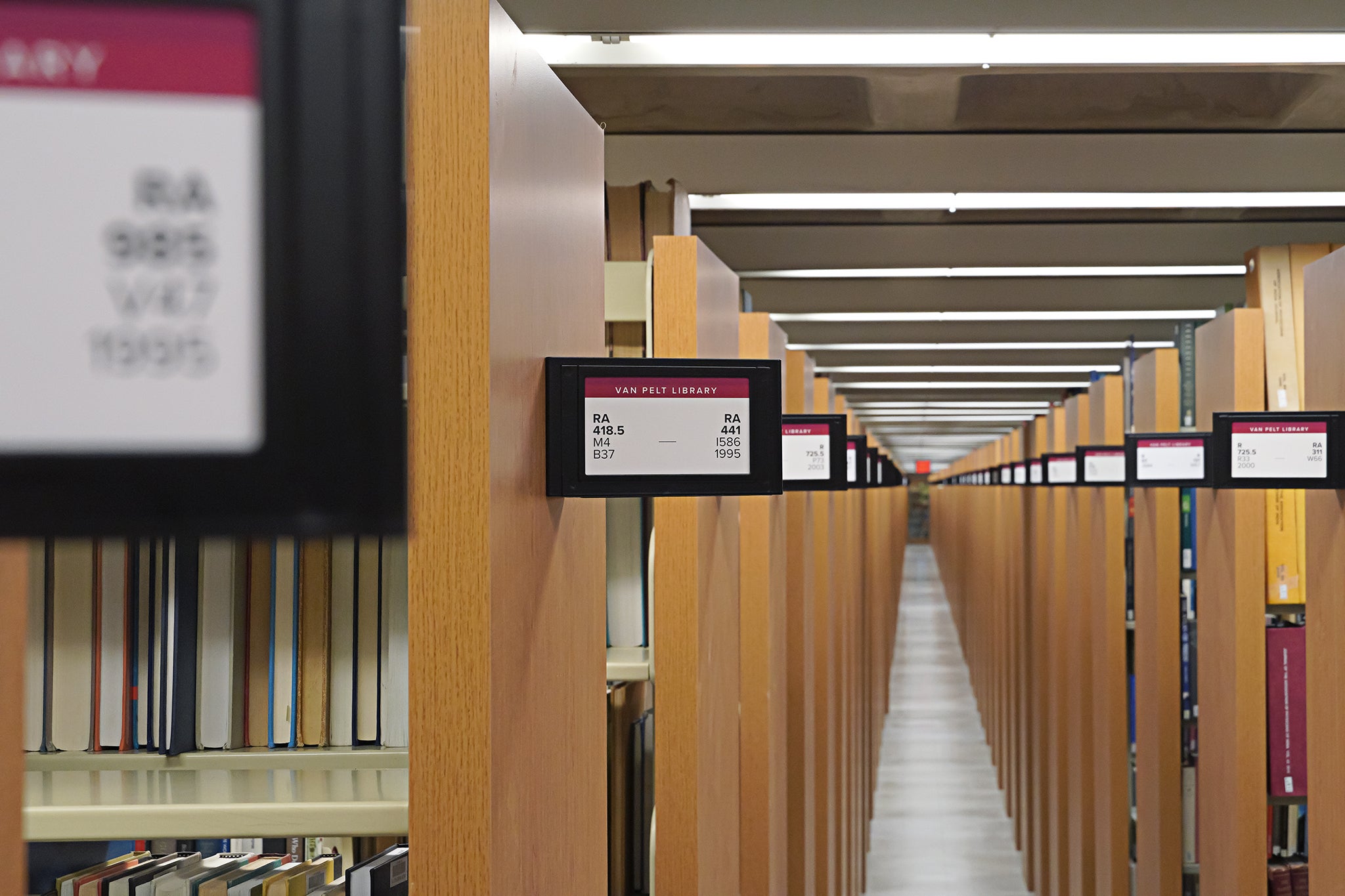 A view of the stacks showing wooden endcaps and range cards with call numbers