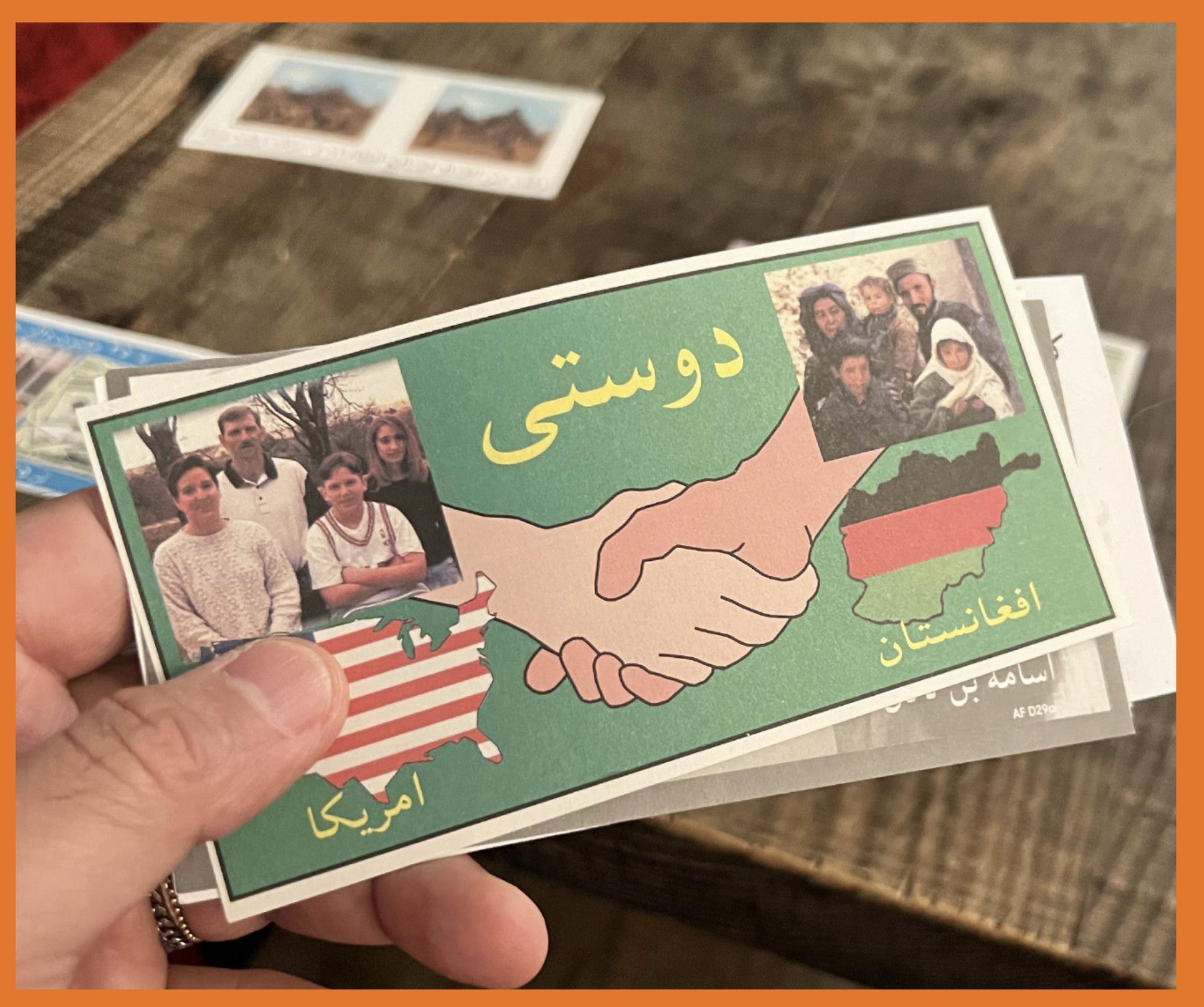 The leaflet shows a photo of an American family over an image of the United States, a photo of an Afghani family over an image of Afghanistan, and a drawing of two hands clasping each other in the center.