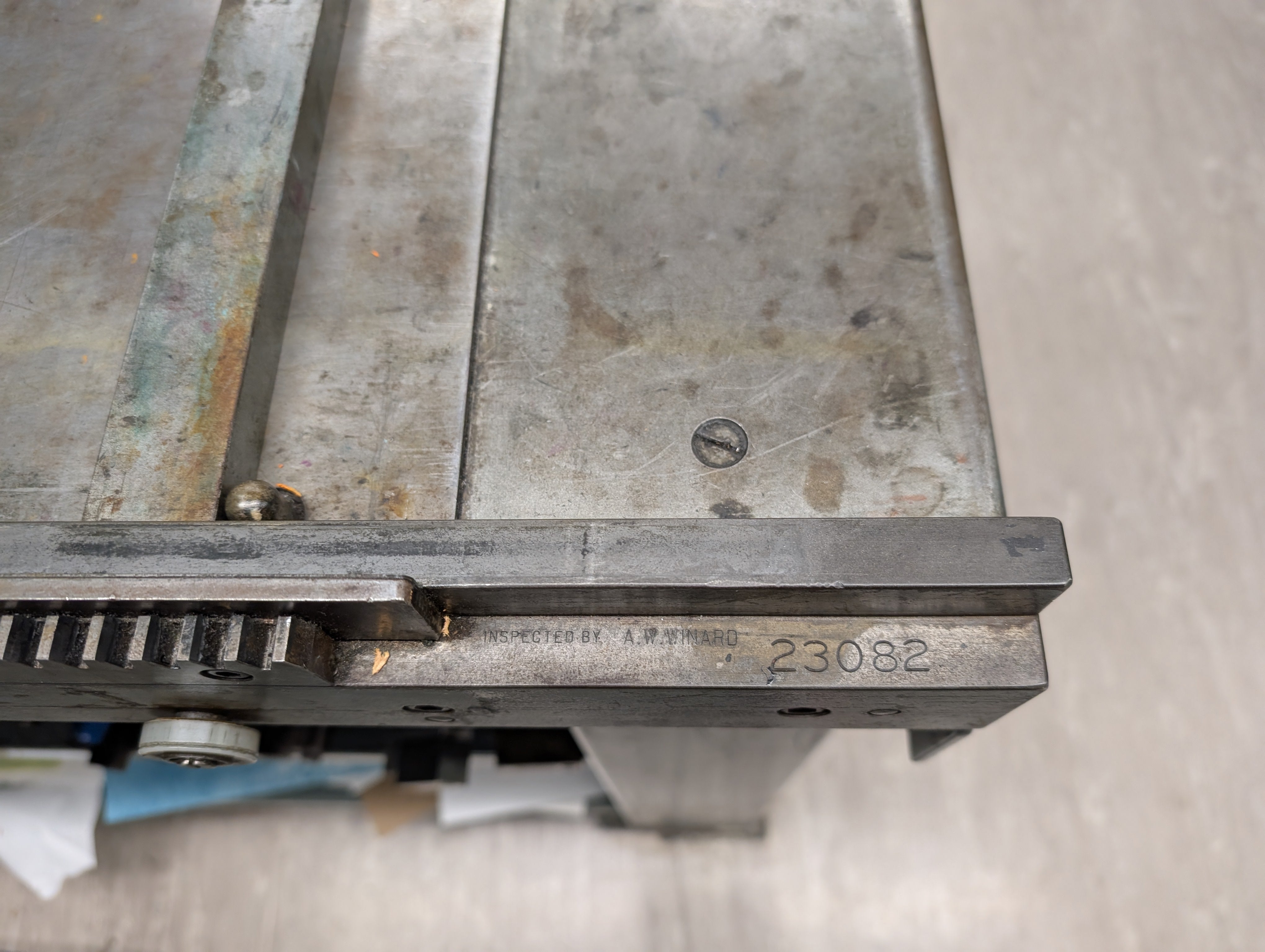 Close up on a metal printing press revealing its serial number.