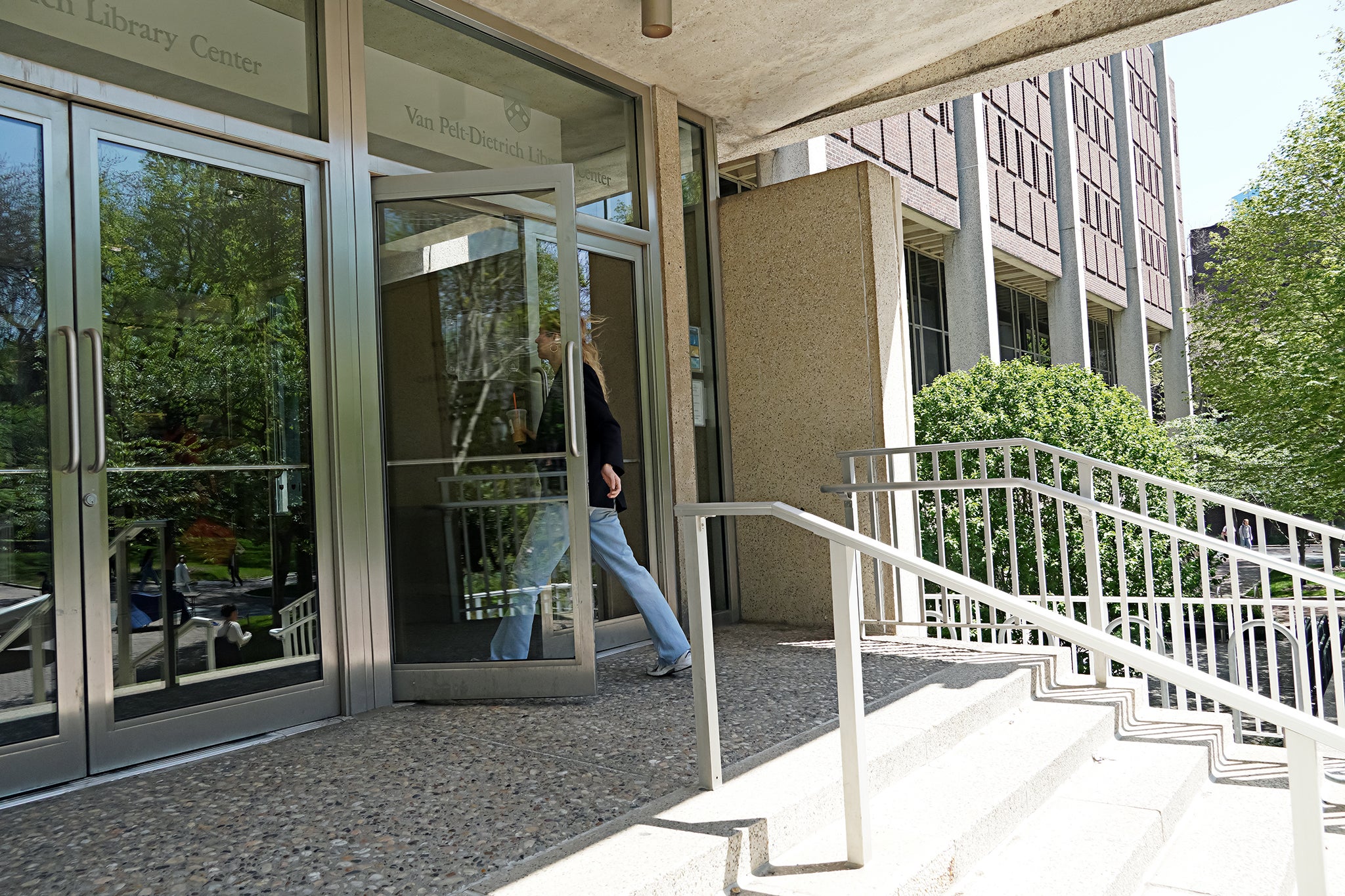 A person walking through glass doors into a large concrete building