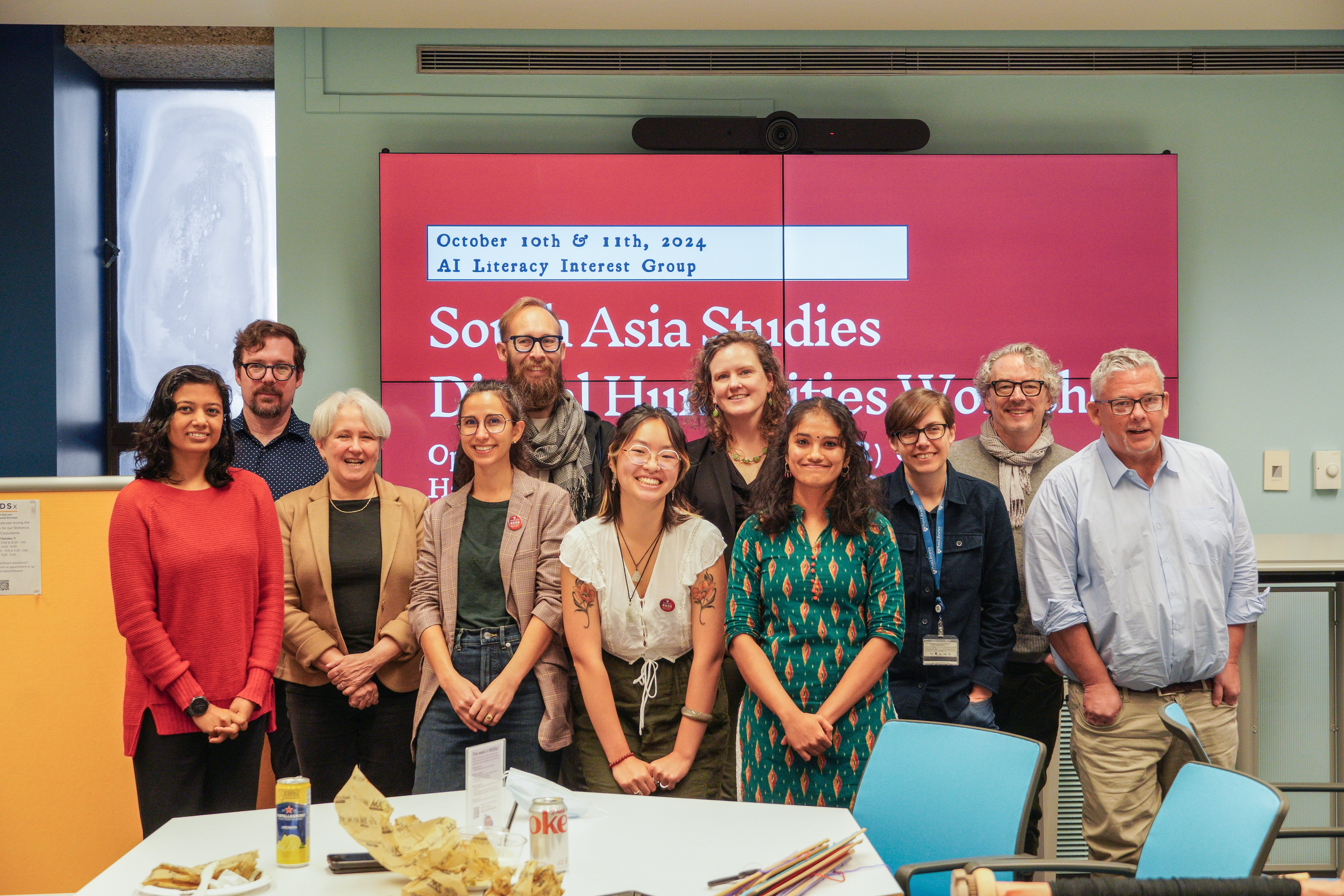 group of people in front a maroon screen with text "South Asia Studies Digital Humanities Workshop"