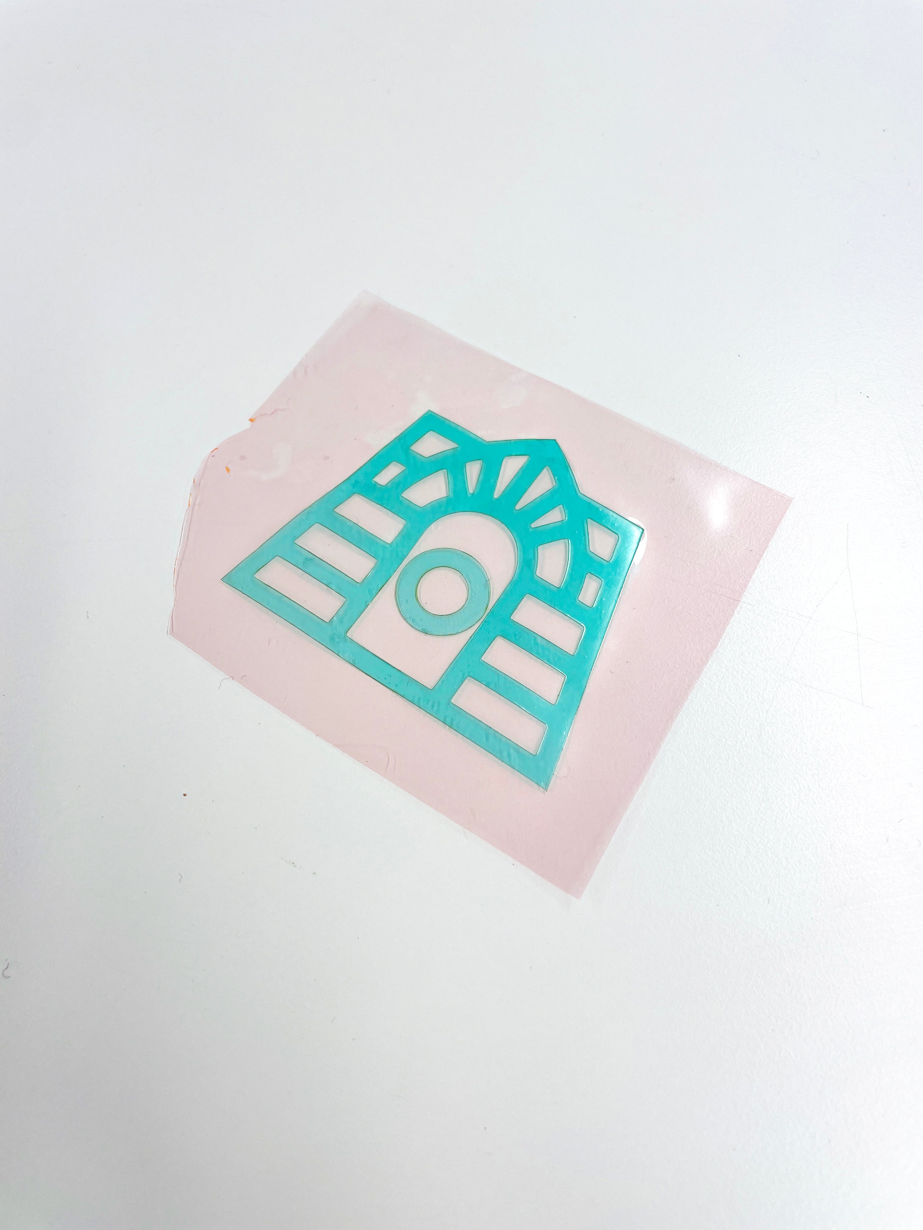  A translucent, pale pink square with a teal, geometric shape in the center, resembling a stylized archway, set against a white background.