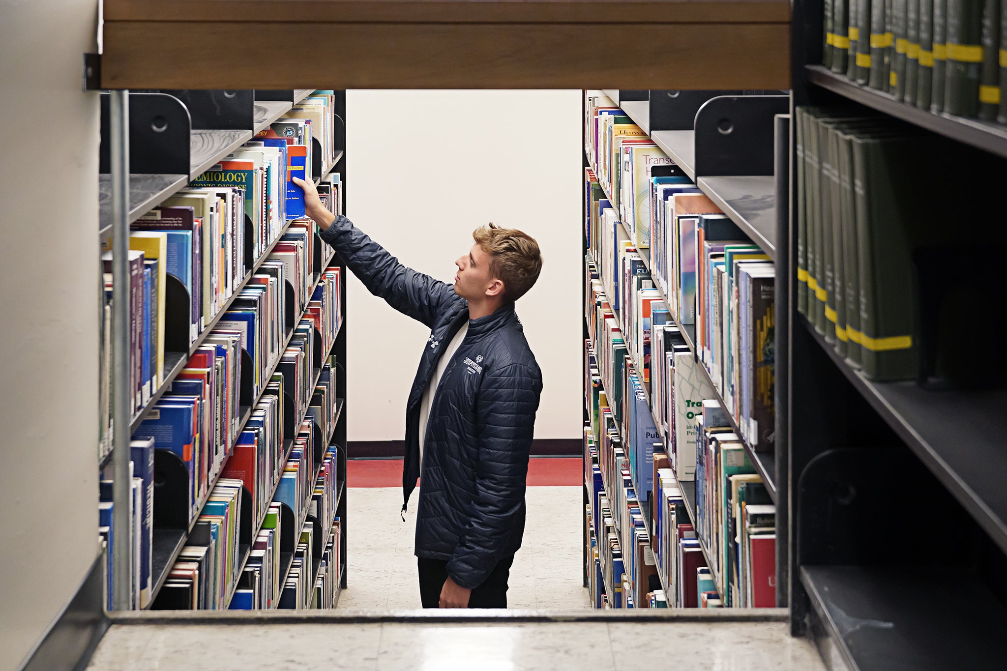 A person pulls a book of a shelf in a library setting.