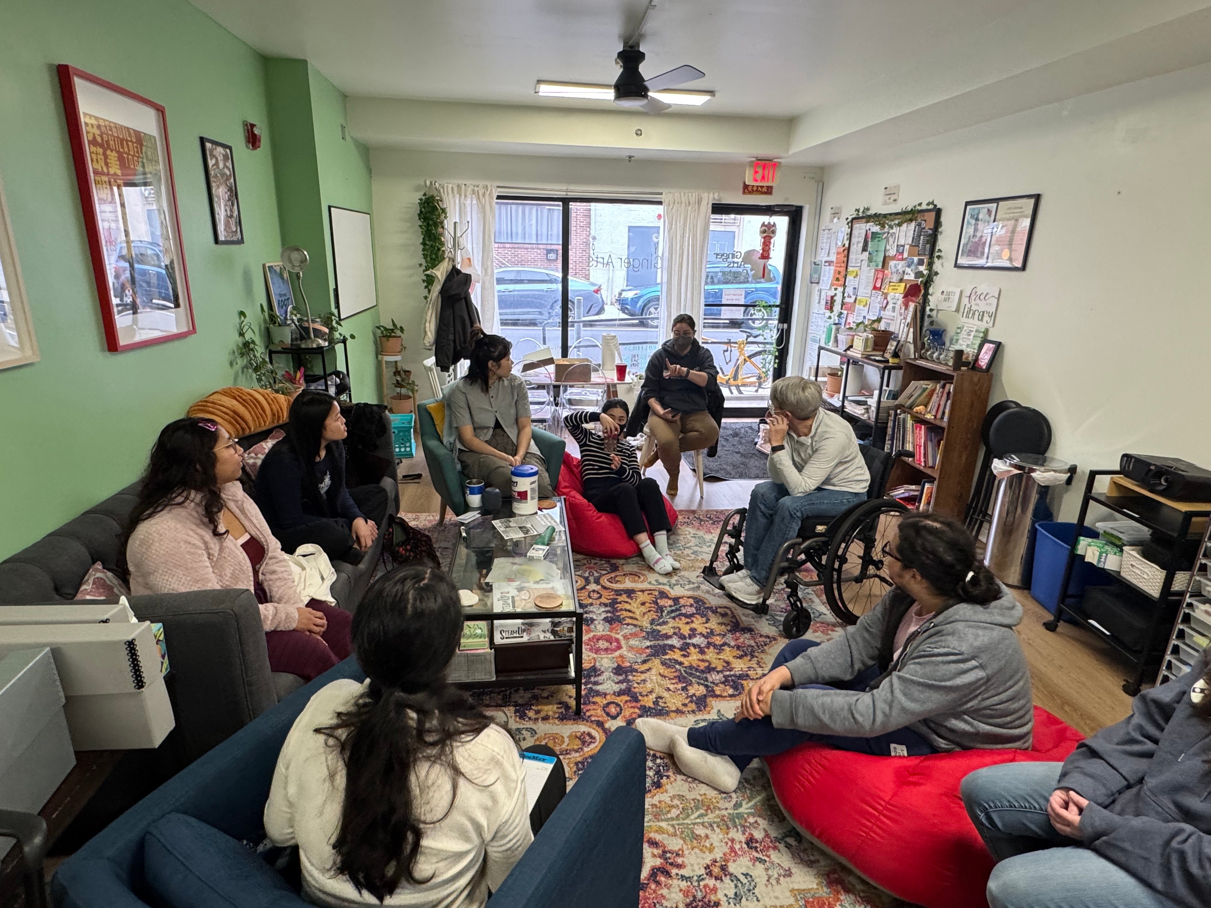 Community members at Ginger Arts sit around a table talking