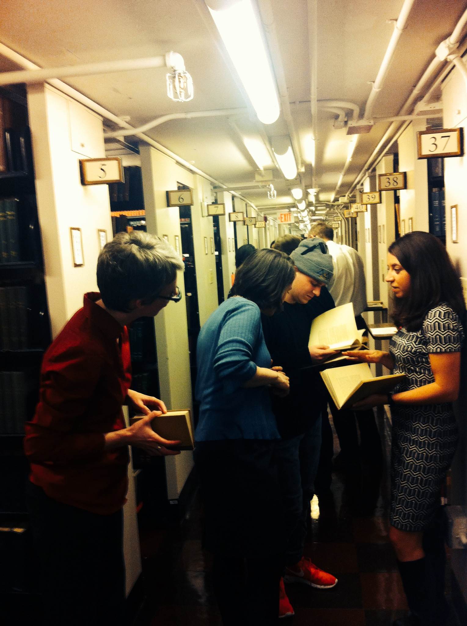 Young readers holding books and chatting in library stacks.