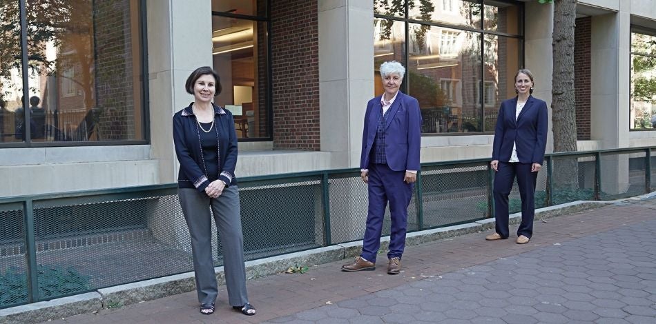 Three people standing outside the renovated building in formal wear.