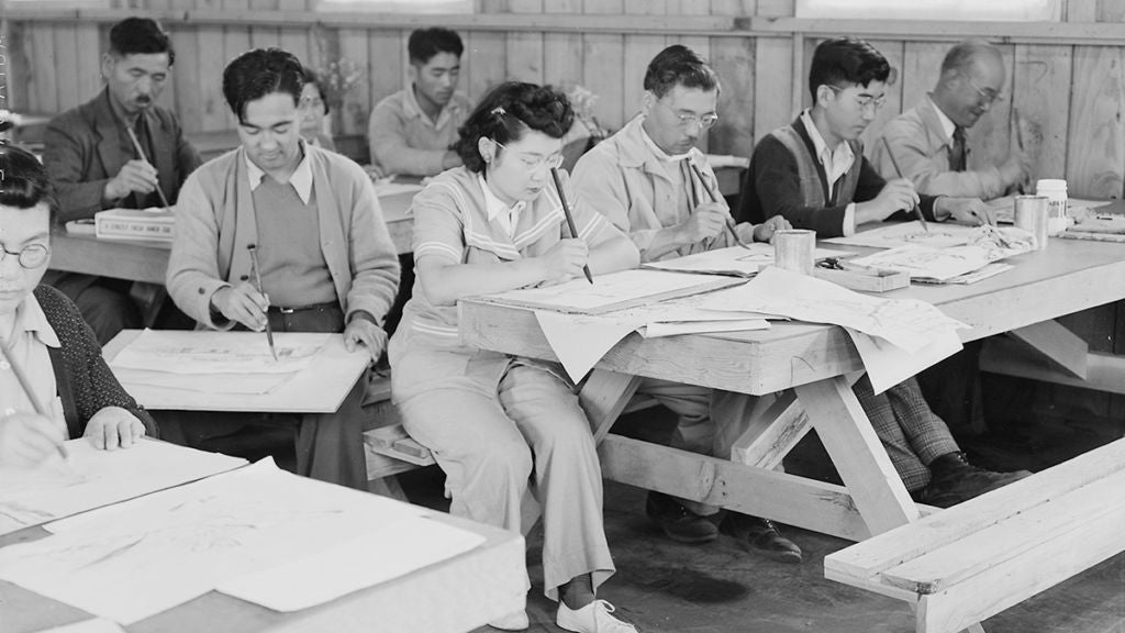 Photo of people working at tables in a classroom. 