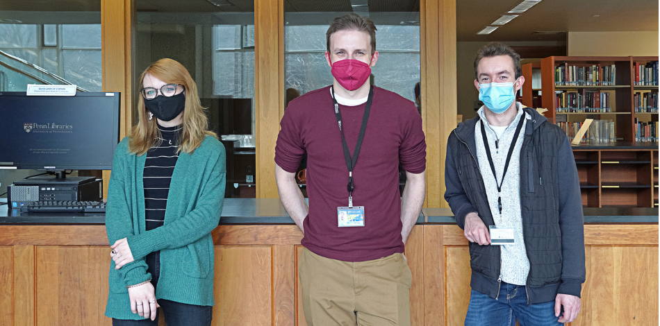 Three people standing in front of the front desk at Van Pelt Library.