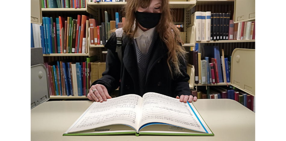 A student sitting in the Van Pelt Library is reading a book.