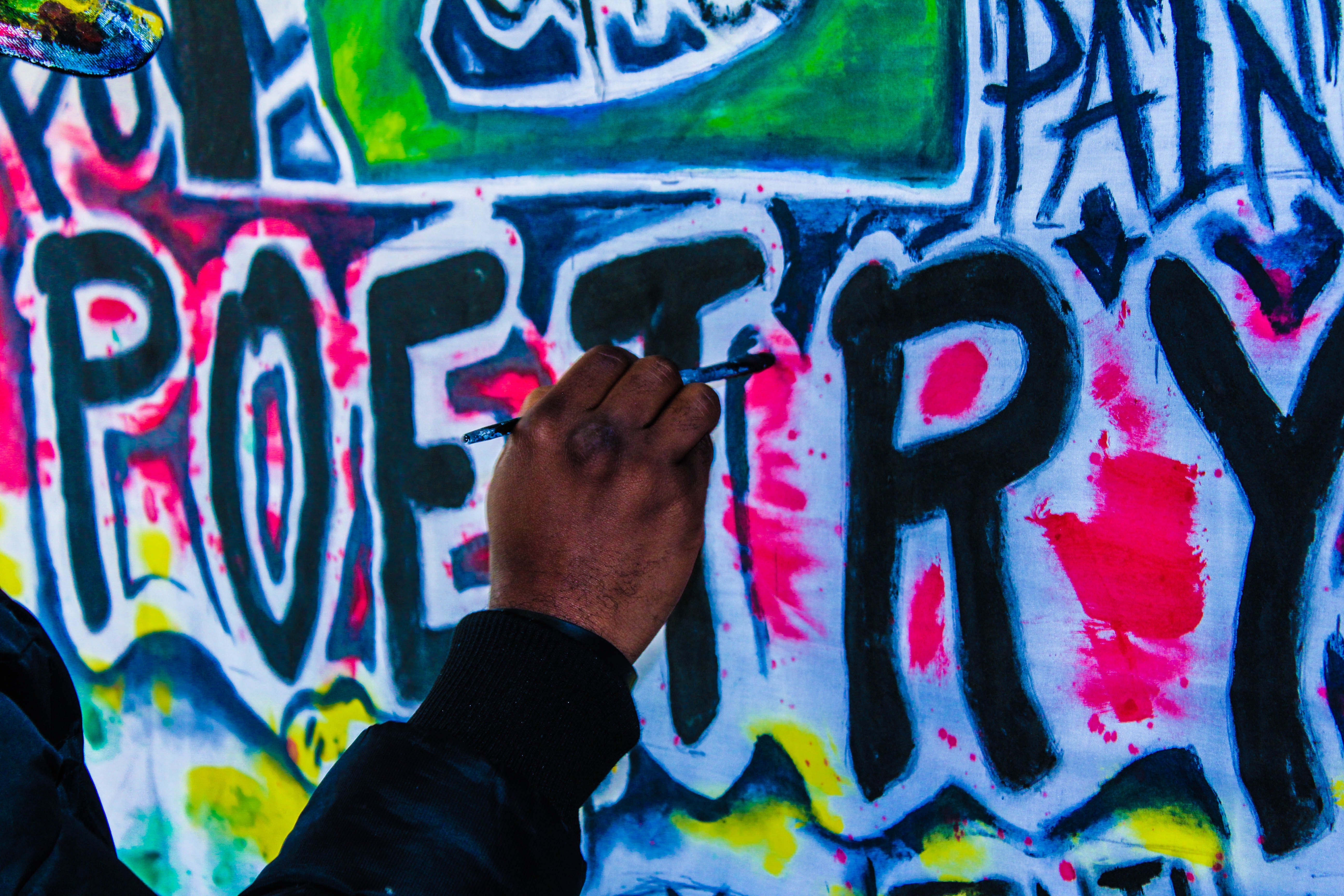 Raised fist in front of a wall with "Poetry" written in colorful lettering.