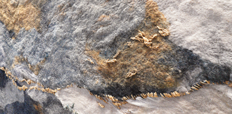 Close up of a mural made from blue, brown, and cream wool and silk.