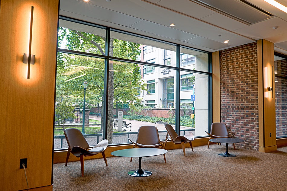 Four chairs and two tables assembled in front of a large window with a view of trees and paved paths.