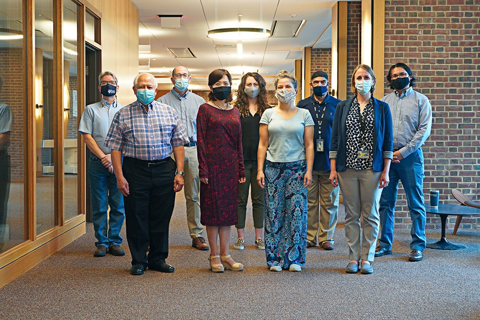 Biotech Commons staff stand in hallway with Assistance desk in background.