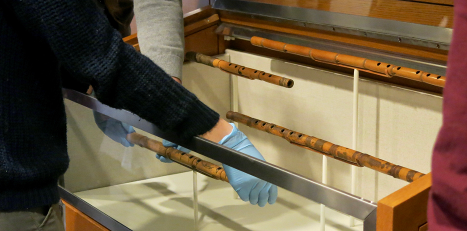 Four ney flutes being placed in a display case.